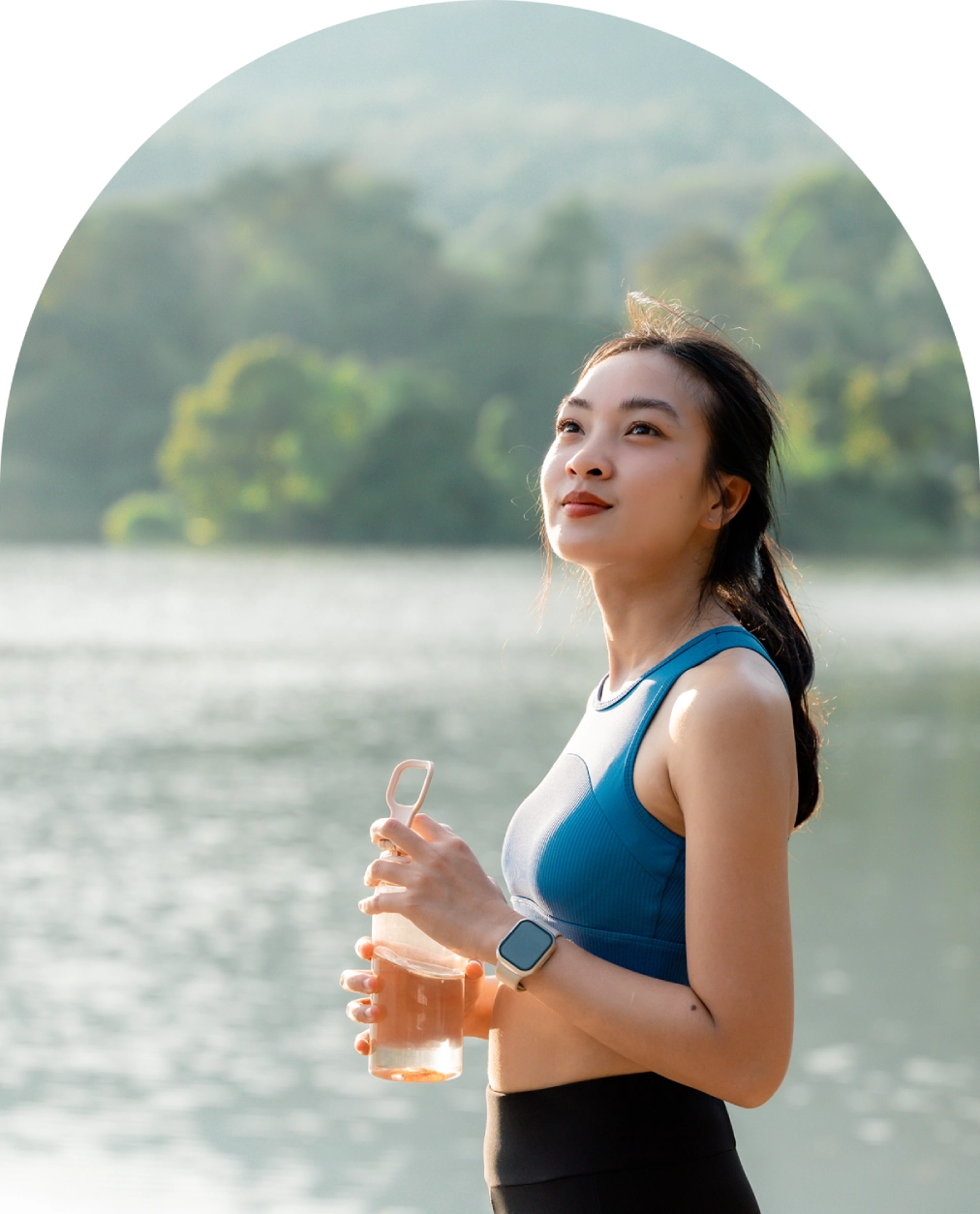 Woman holding water bottle by a lake. Woman holding water bottle by a lake.